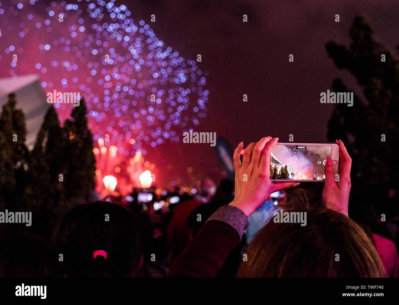Woman photographing fireworks using smartphone during Chinese New Year celebrations in Kowloon in Hong Kong. Stock Photo