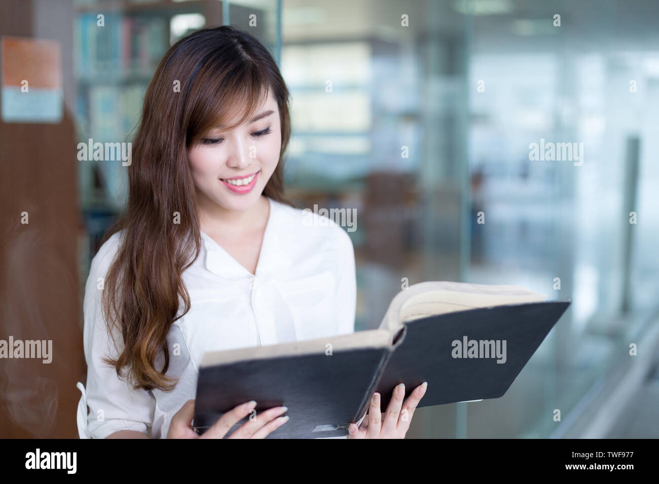 Asian beautiful female student holding book in library Stock Photo - Alamy