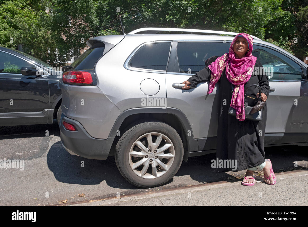 A Muslim woman in a hijab waits to pick up a child outside P.S. 69 in Jackson Heights, Queens, New York City. Stock Photo
