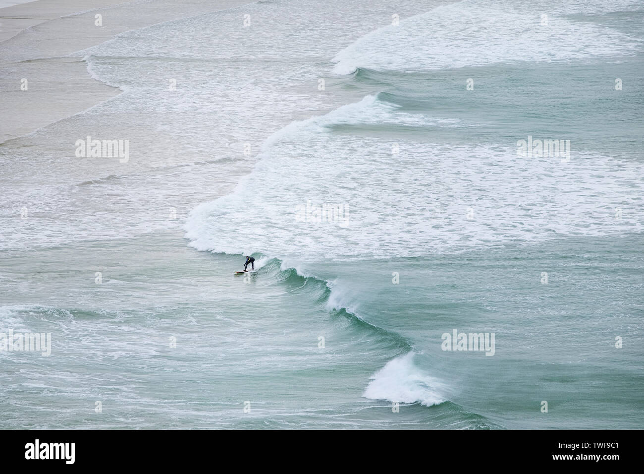 A lone surfer riding a wave at Crantock Beach in Newquay in Cornwall. Stock Photo