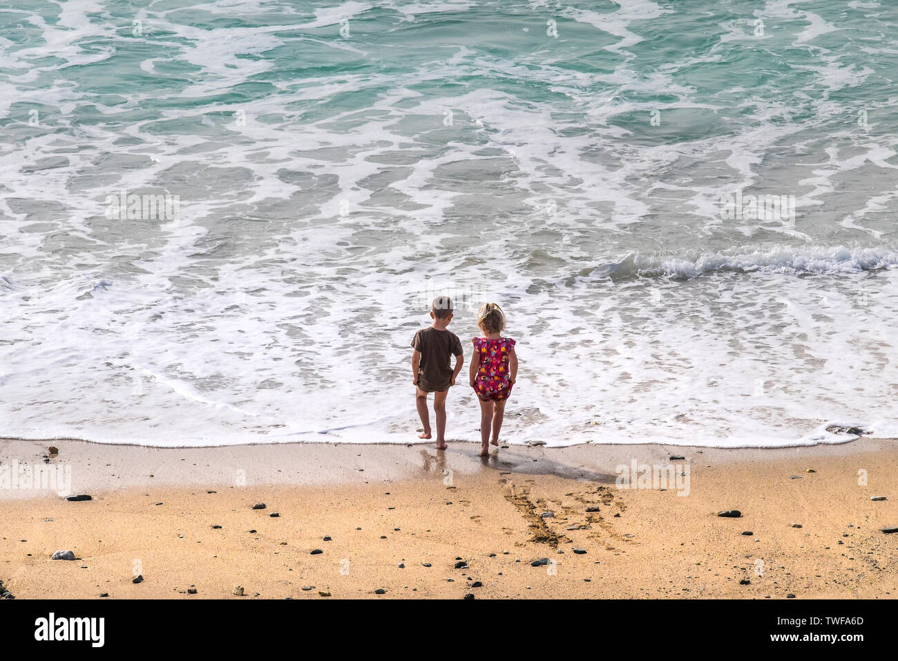 Two young children paddling in the sea at Fistral Beach in Newquay in Cornwall. Stock Photo