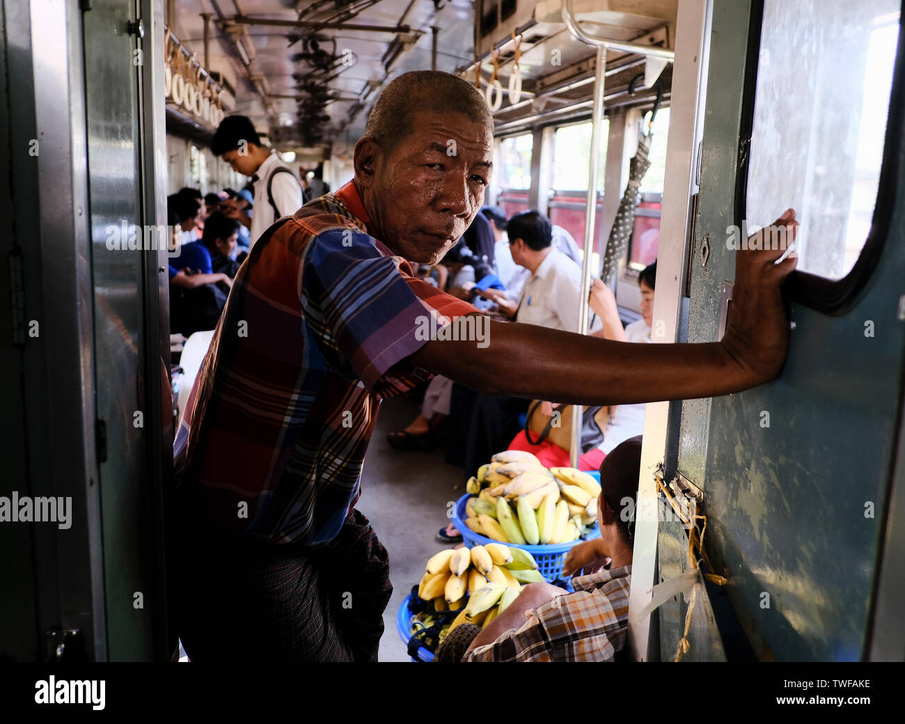 A Burmese man stands in a busy commuter train in Yangon city. Stock Photo