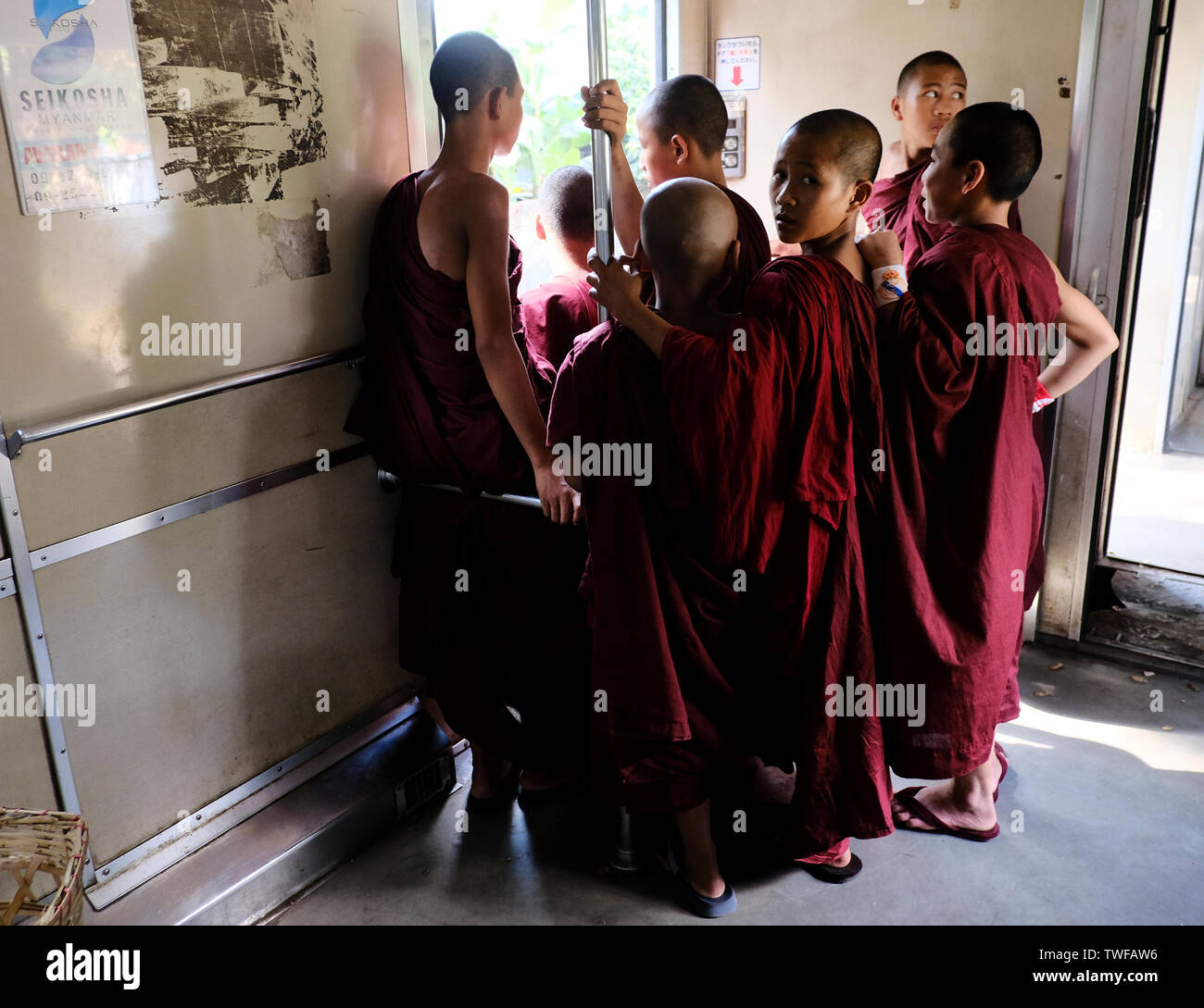 Young Buddhist monks stand in a Burmese train carriage in Yangon City. Stock Photo