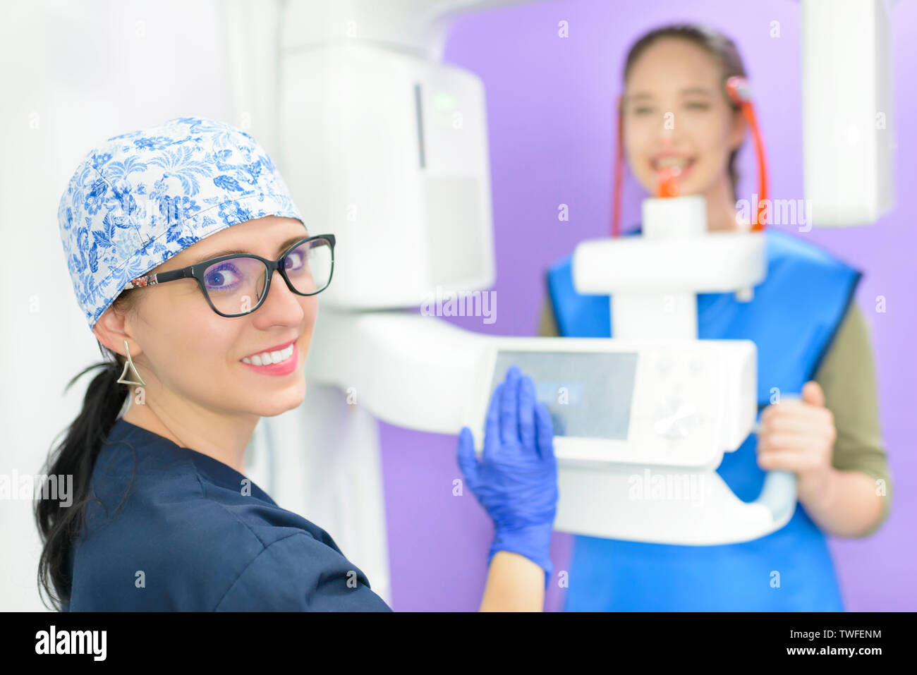 Beautiful young woman patient getting dental radiography. Dentist doctor preparing radiology equipment. Stock Photo