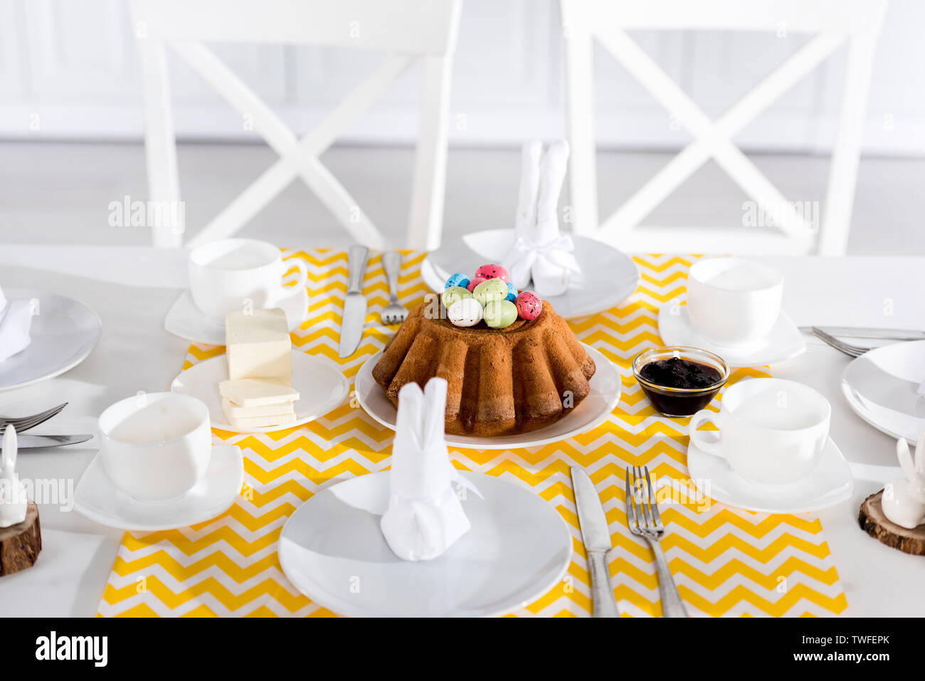 Easter cake with painted eggs and crockery on table Stock Photo