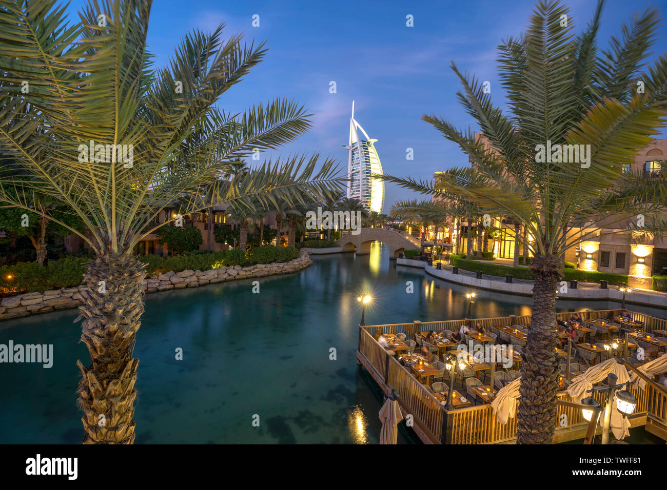 The beautiful waterfront of Souk Madinat Jumeirah and the 7-star hotel Burj al Arab are framed by elegant palm trees in Dubai. Stock Photo