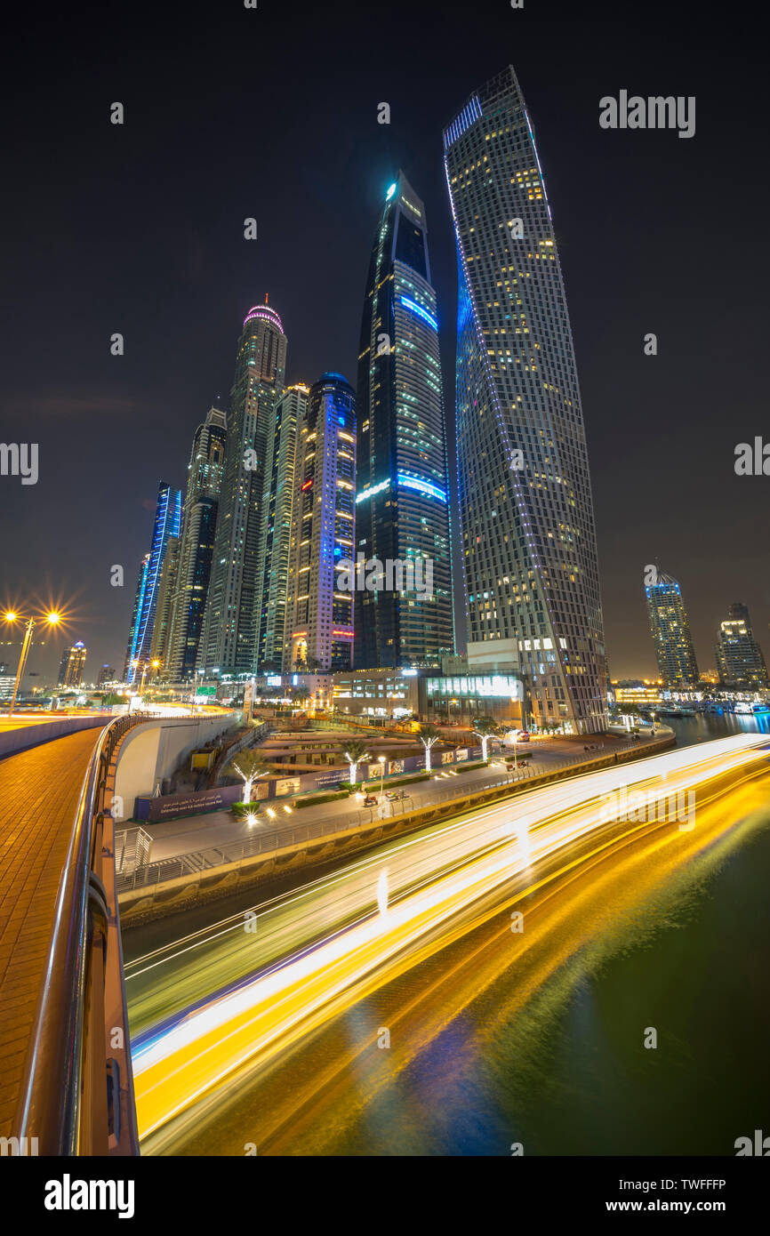 The light trails of a dinner cruise stream past in the Dubai Marina. Stock Photo