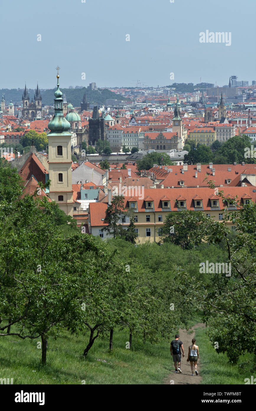 View on orchard and Church of Our Lady Victorious with Lesser Lower of Prague with a couple walking through vineyard in Prague, Czech Republic Stock Photo