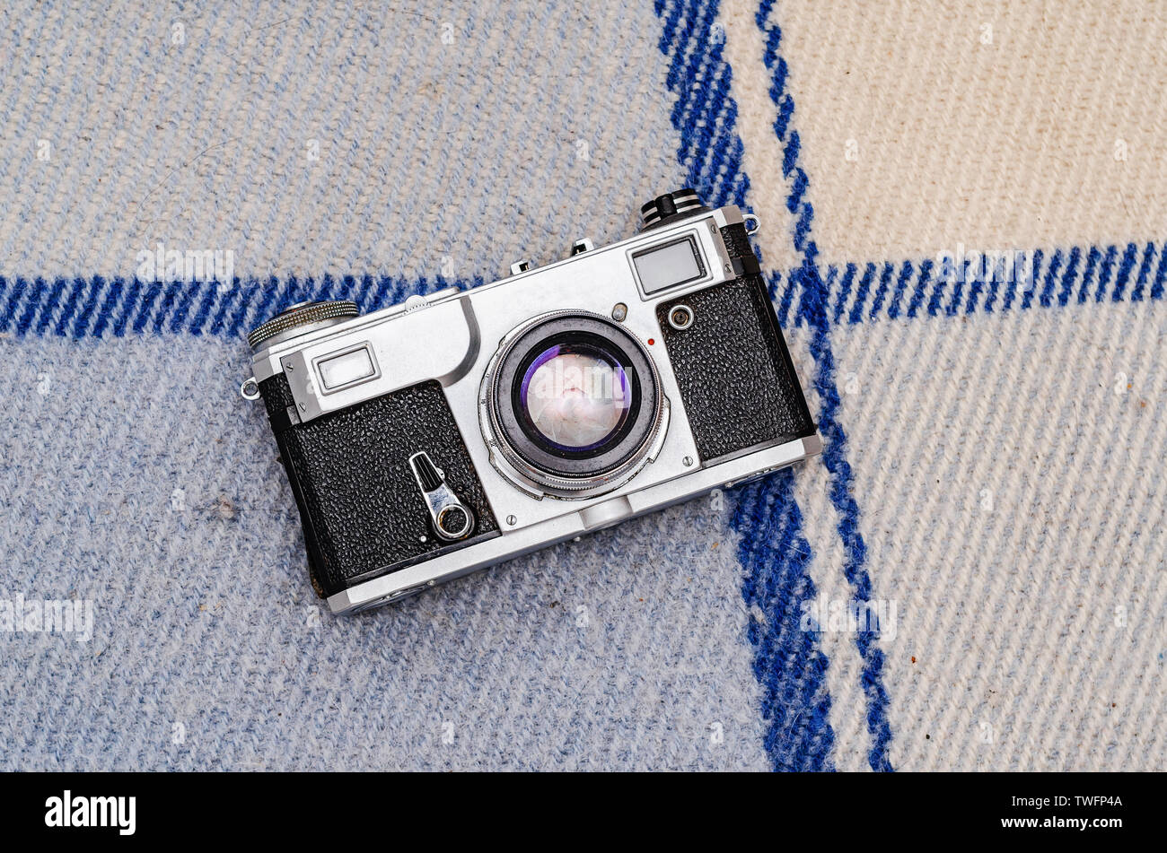 Film camera on a plaid on white boards. Stock Photo