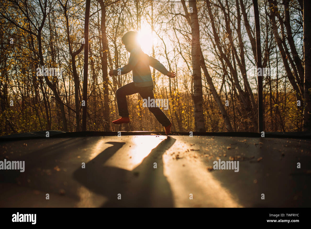 Silhouette of a boy on a trampoline at sunset Stock Photo