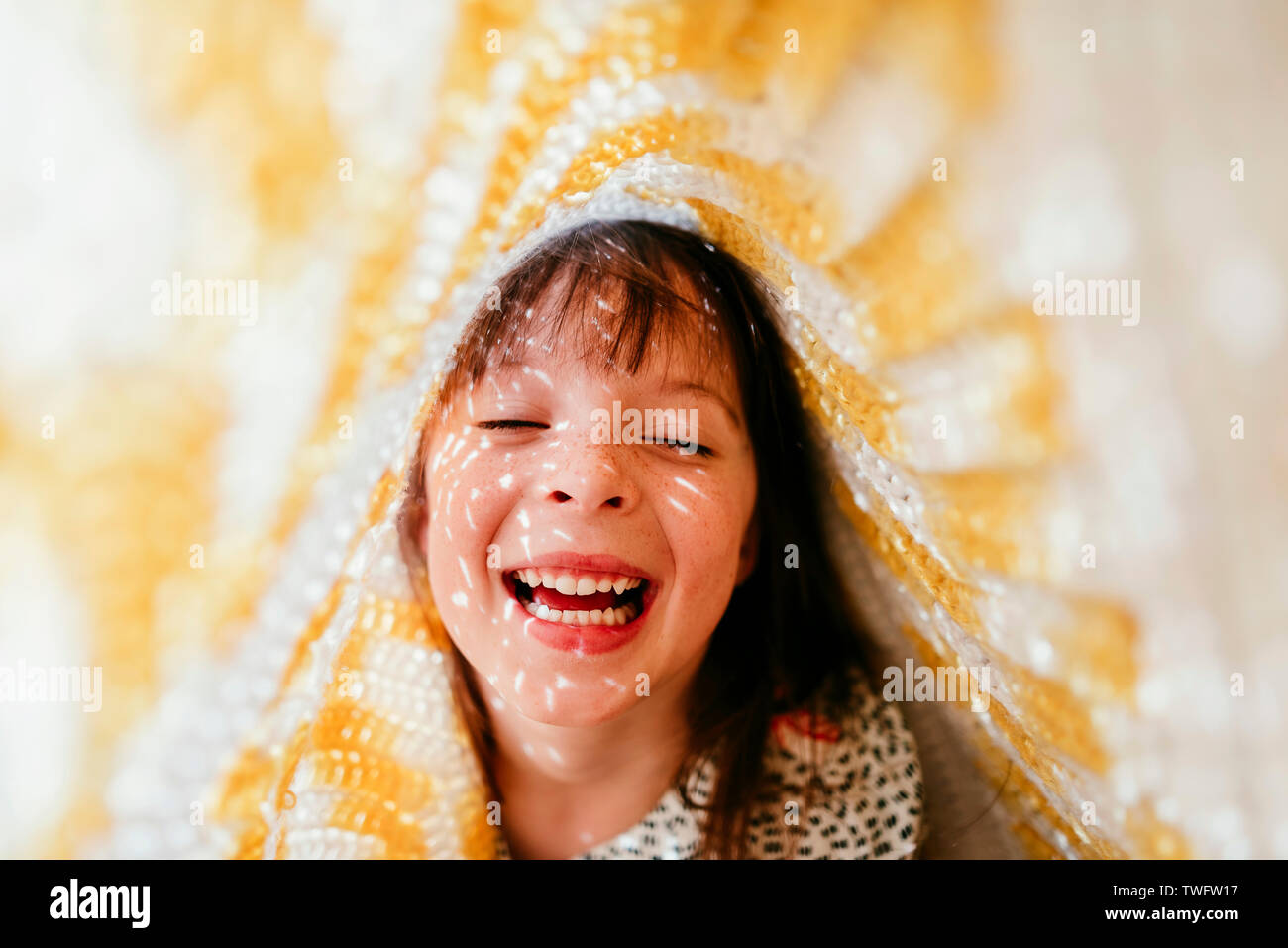 Portrait of a girl hiding under a blanket laughing Stock Photo Alamy