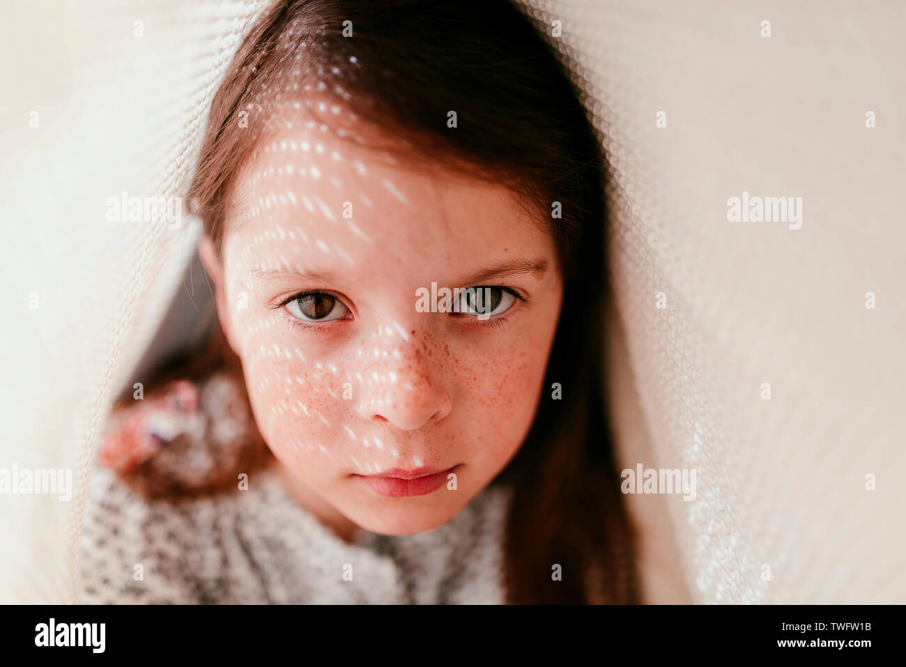 Portrait of a girl hiding under a blanket Stock Photo