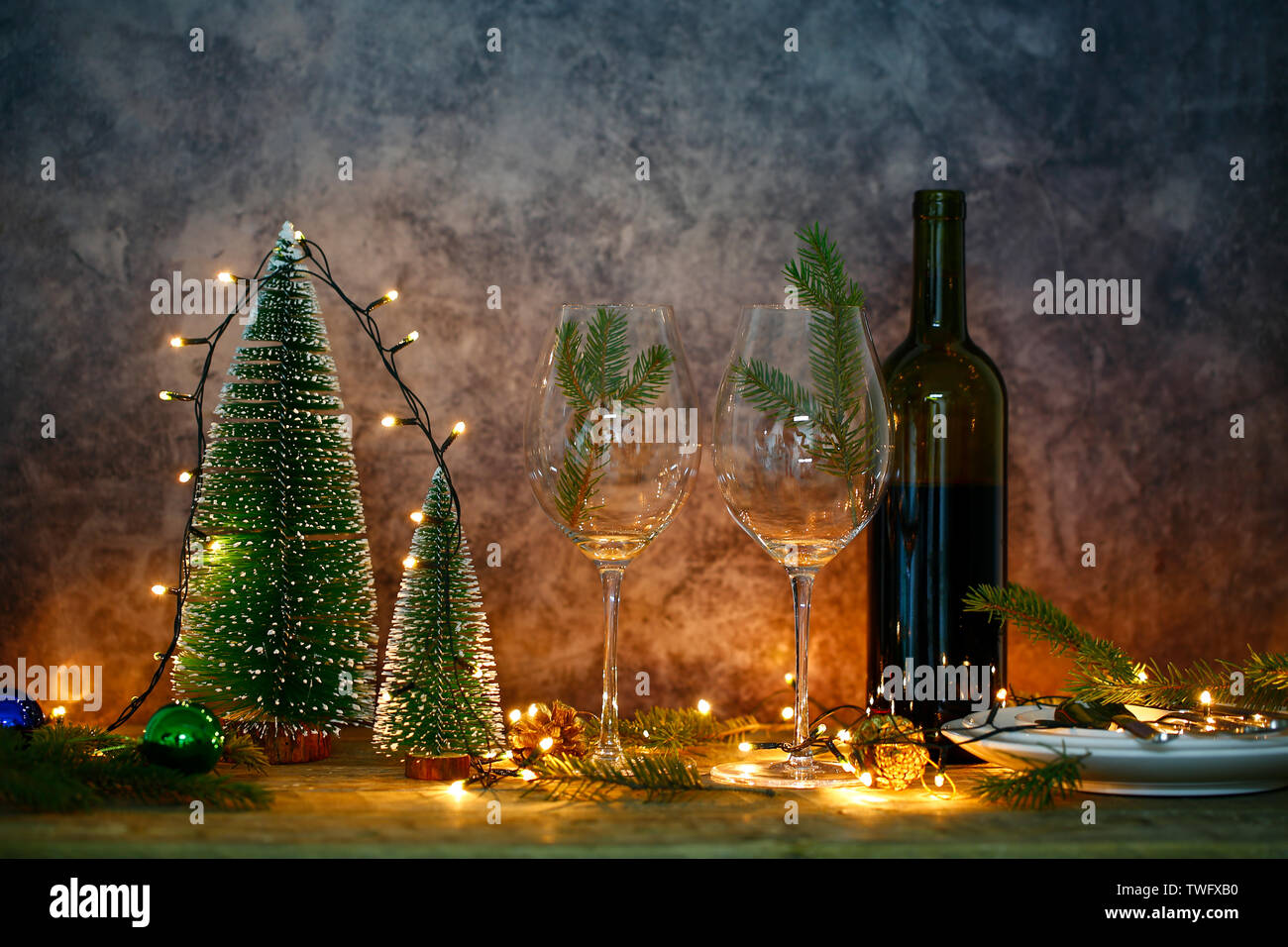 Red wine on the table with Christmas tree. Dining table and lights for