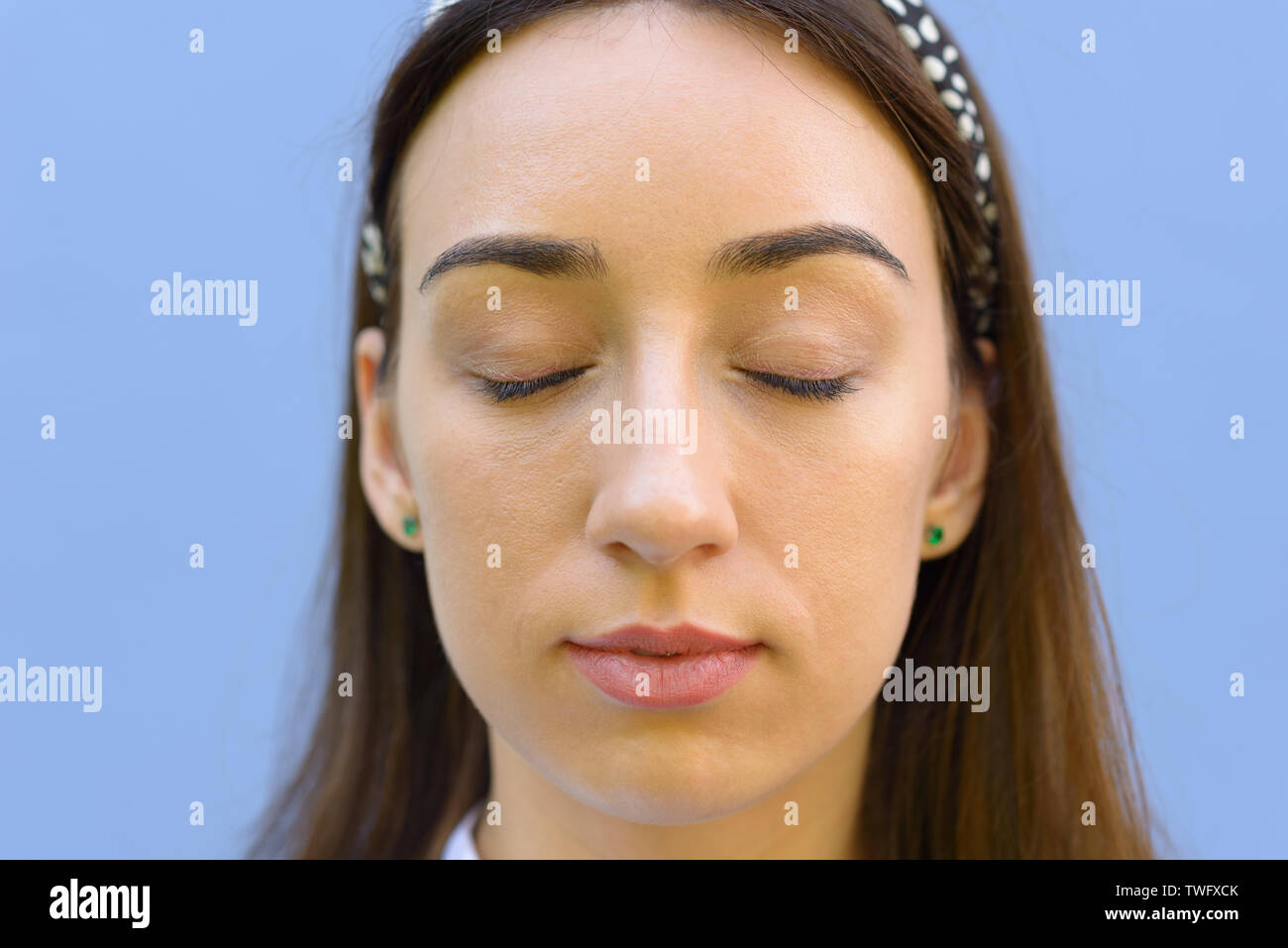 Young woman with a serene expression and closed eyes in a close up ...