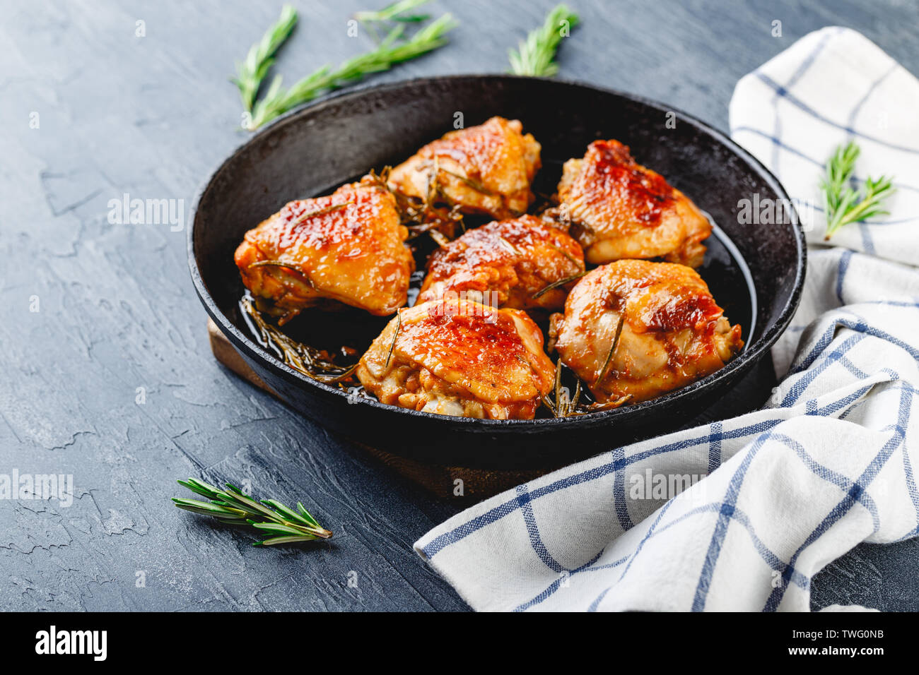 Chicken thighs fried with rosemary in a cast iron skillet and rosemary
