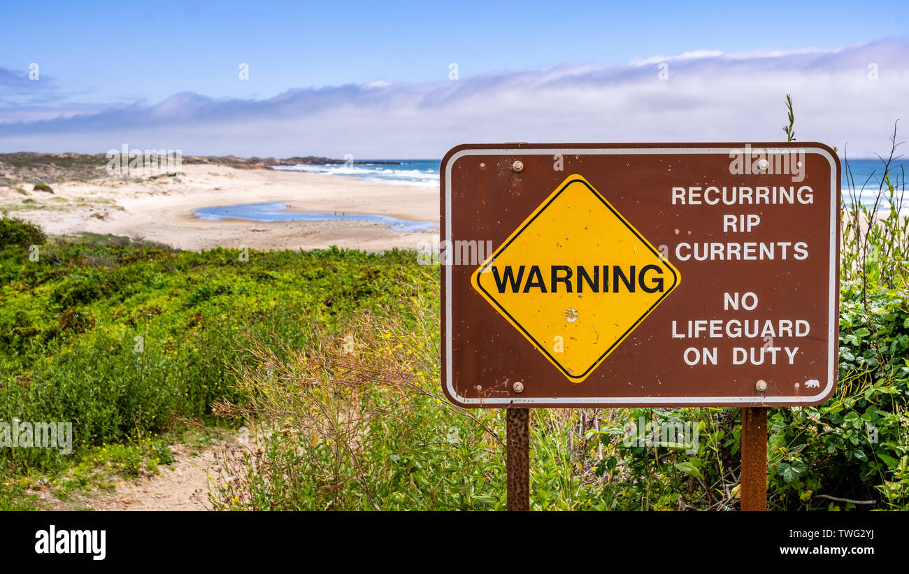 Warning regarding recurring rip currents and no lifeguard on duty posted on the Pacific Ocean coastline, California Stock Photo