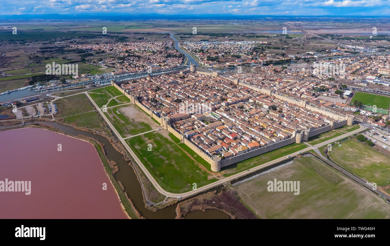 Medieval stone fortified fortress town Aigues-Mortes in France. This city stands on canals and a pond with pink salt water. Aerial view. Stock Photo