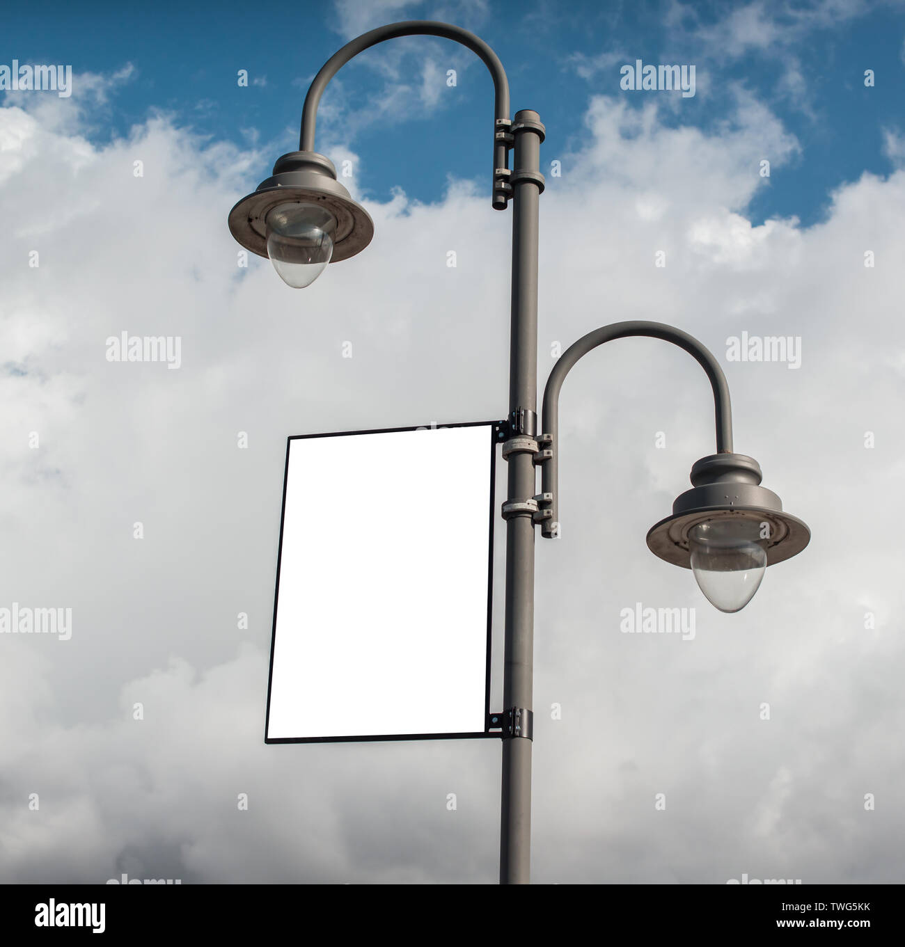 White blank rectangular billboard on a lamppost on a cloudy sky background. Stock Photo