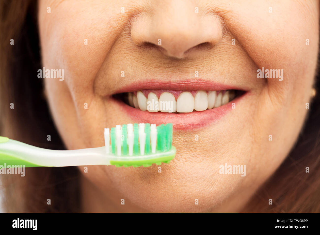 senior woman with toothbrush brushing her teeth Stock Photo