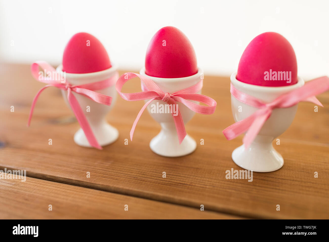 three pink colored easter eggs in holders on table Stock Photo