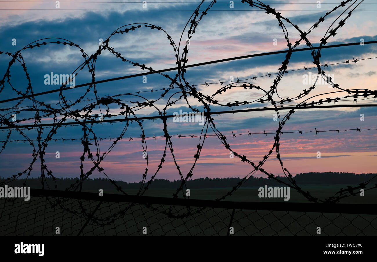 beautiful sunset behind the fence with barbed wire Stock Photo - Alamy