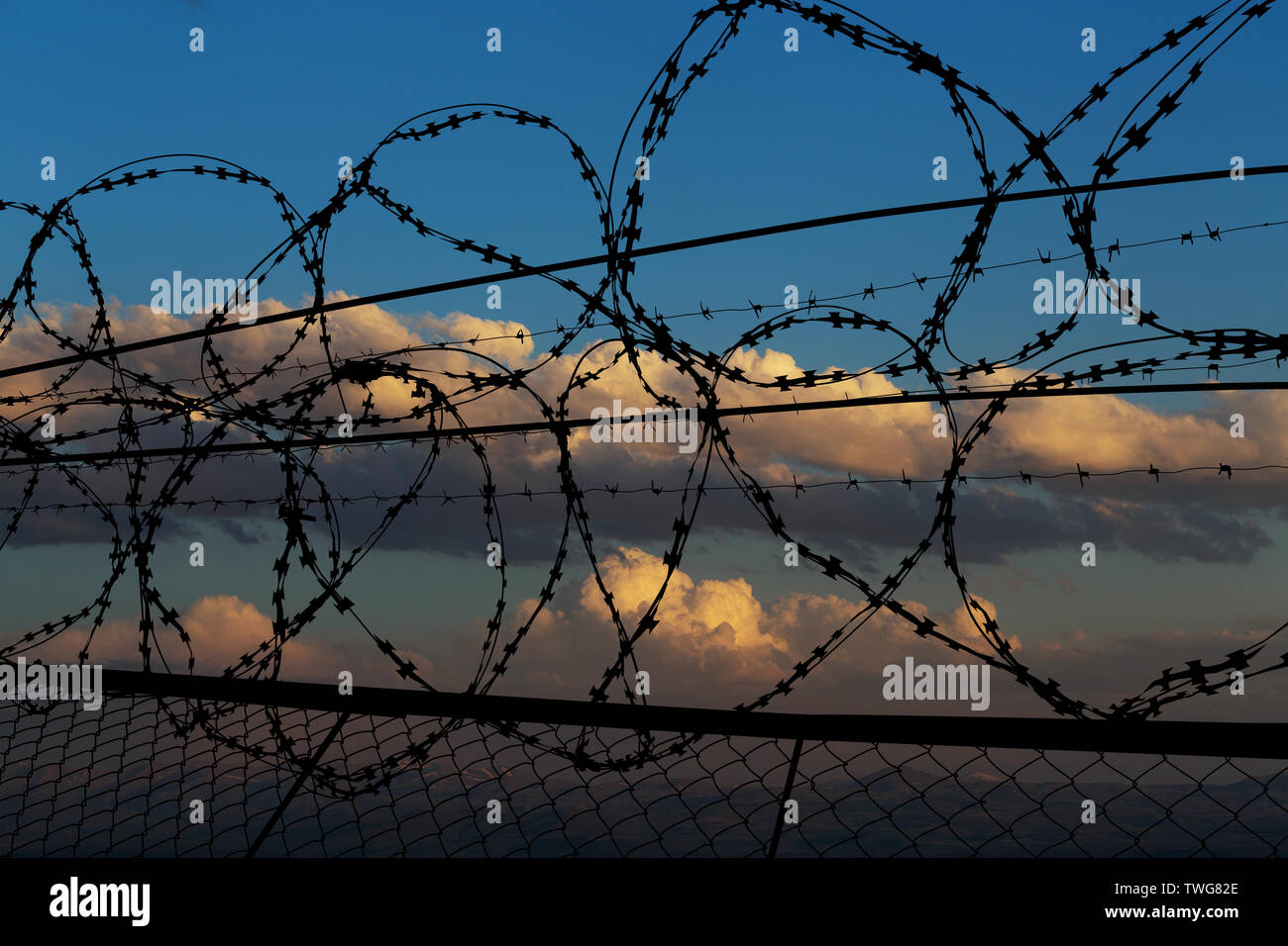 beautiful sunset behind the fence with barbed wire Stock Photo - Alamy