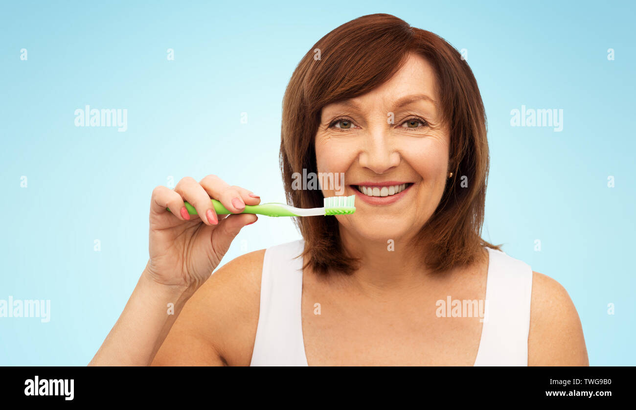 senior woman with toothbrush brushing her teeth Stock Photo
