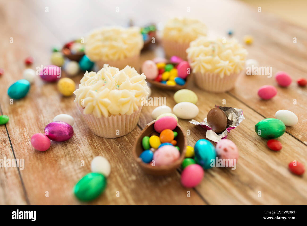 cupcakes with chocolate eggs and candies on table Stock Photo