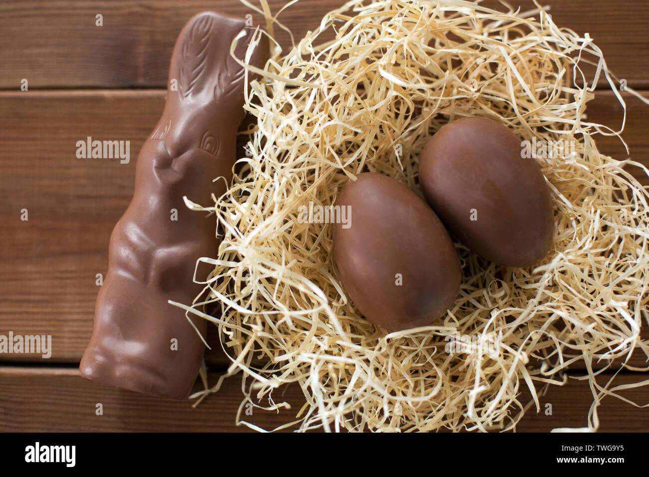 chocolate bunny and eggs in straw nest on wood Stock Photo
