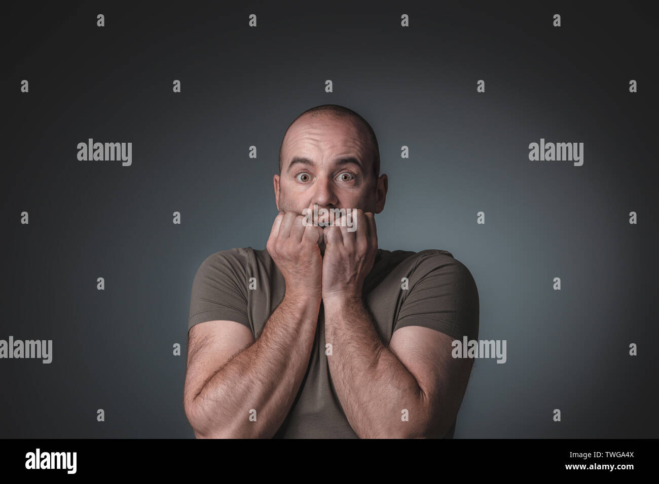 portrait of caucasian man with scared expression bringing his hands to his face, studio shot. Stock Photo