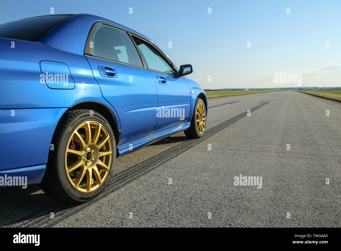 The blue youngtimer sports car with golden rims is standing on the concrete runway of the airport and is ready to drive fast. Stock Photo