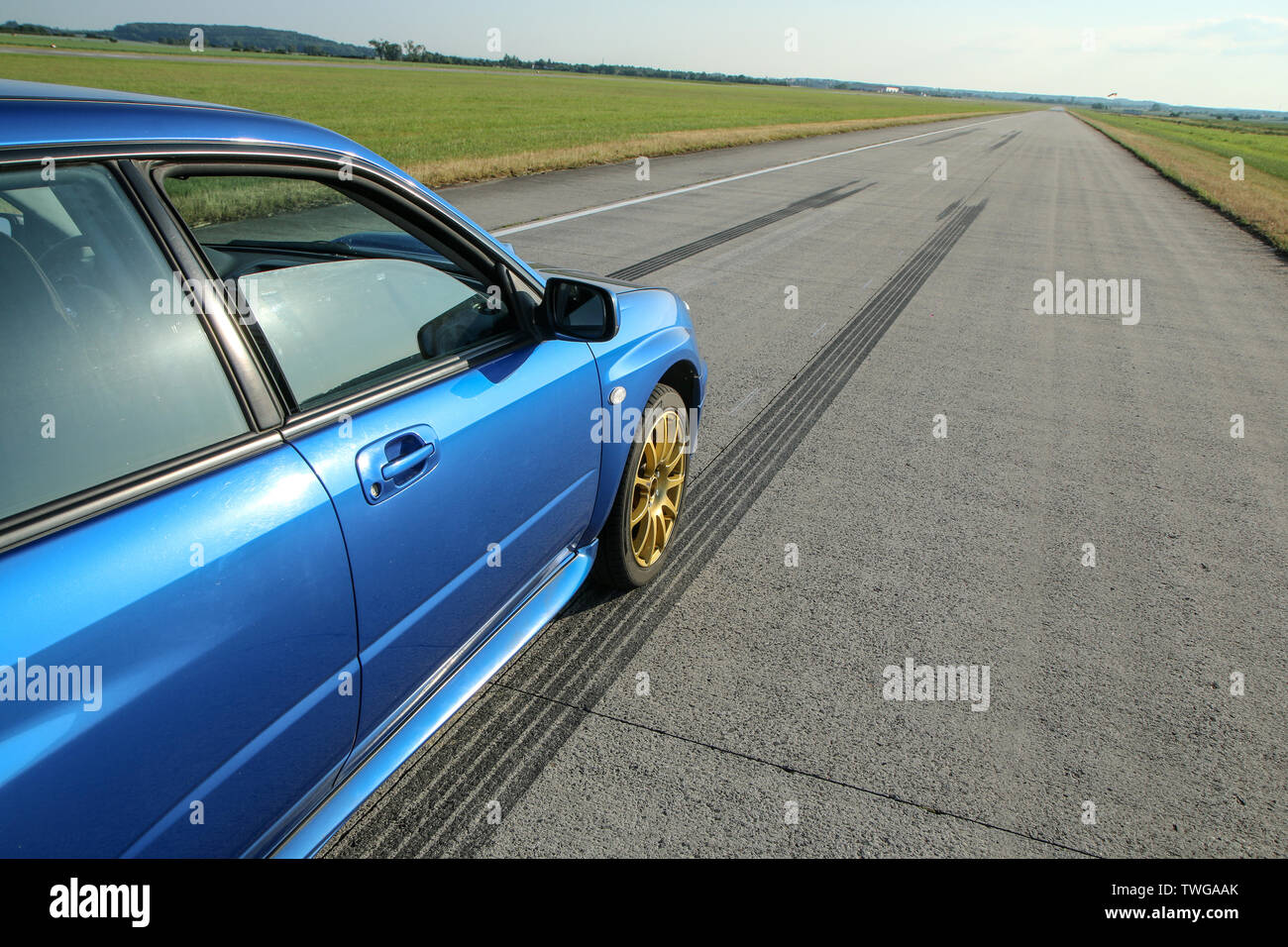 The blue youngtimer sports car with golden rims is standing on the concrete runway of the airport and is ready to drive fast. Stock Photo