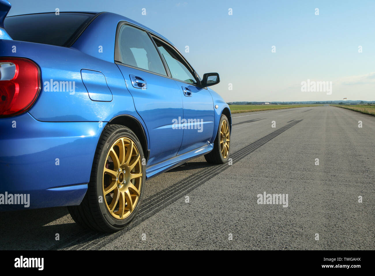 The blue youngtimer sports car with golden rims is standing on the concrete runway of the airport and is ready to drive fast. Stock Photo