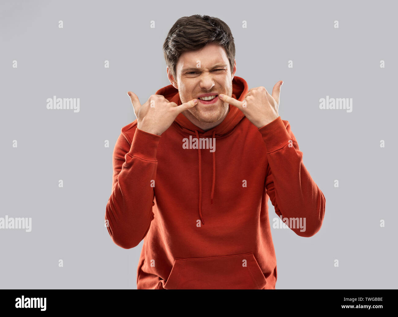 bully young man whistling over grey background Stock Photo