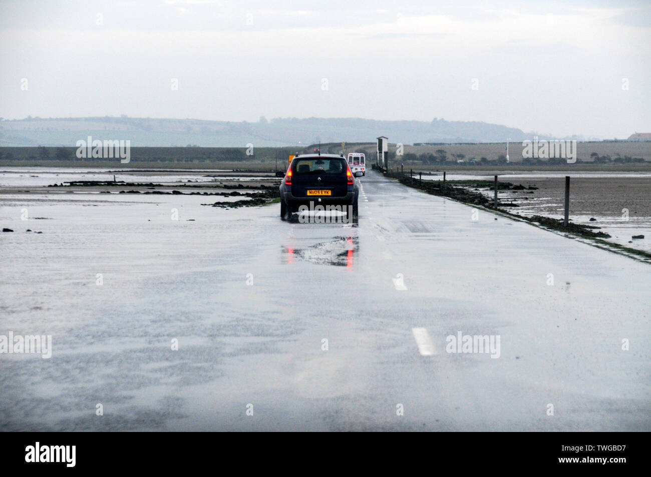 Traffic crossing at low tide along the 3-mile Lindisfarne causeway on Lindisfarne Holy Island, a tidal island in Northumberland, Britain. Holy Island Stock Photo