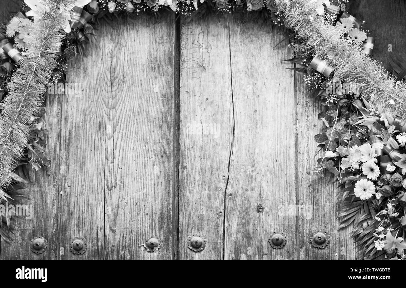 Floral archway on old wooden door with copy space in stunning black and white Stock Photo