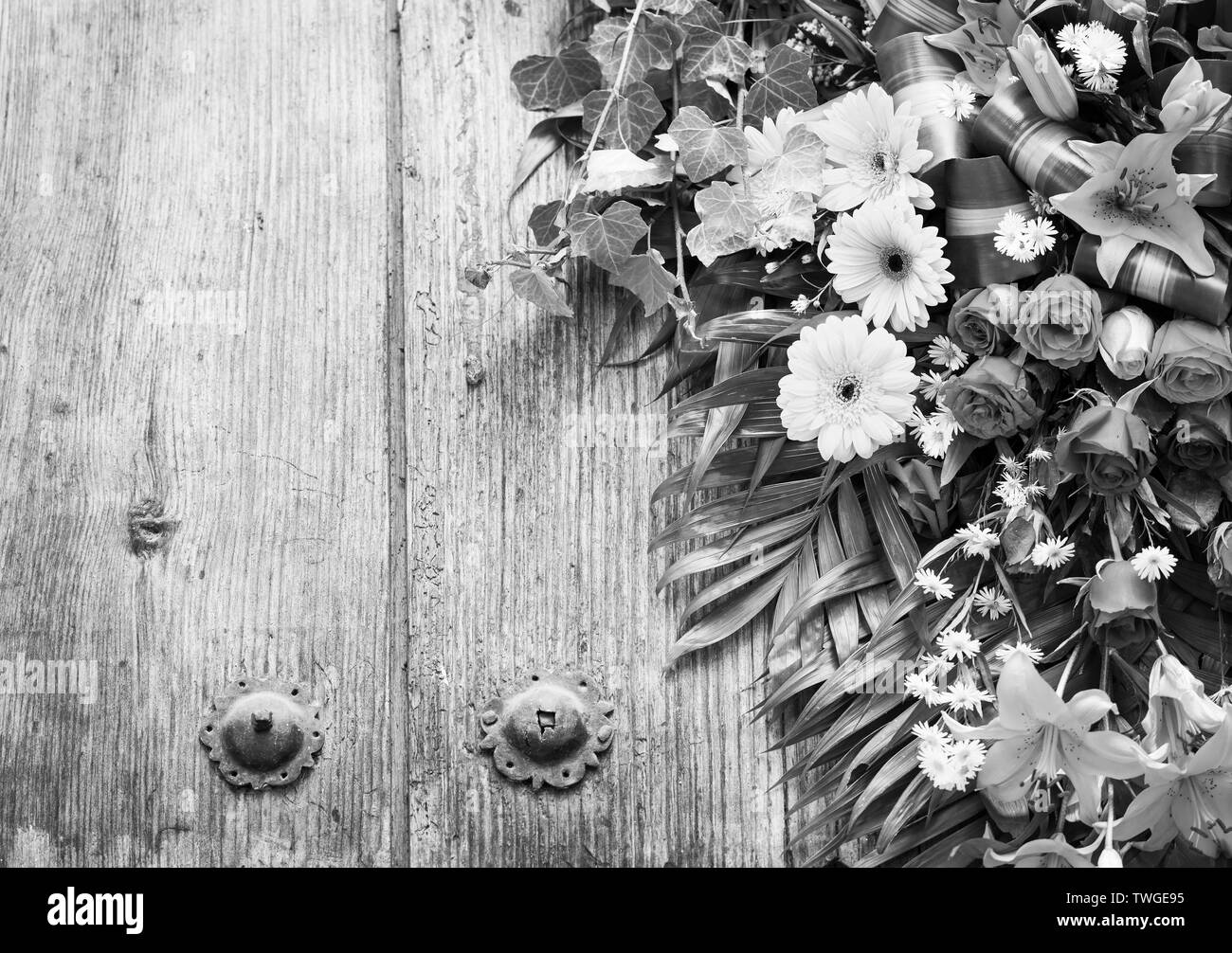 Floral wreath on weathered wooden door with copy space in stunning black and white Stock Photo