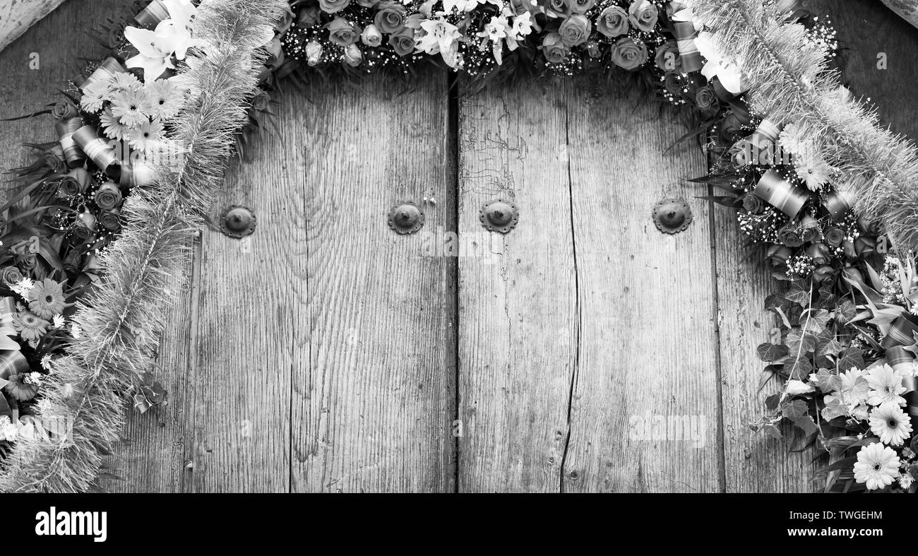 Flower arrangement on old timber door as textured background in stunning black and white Stock Photo