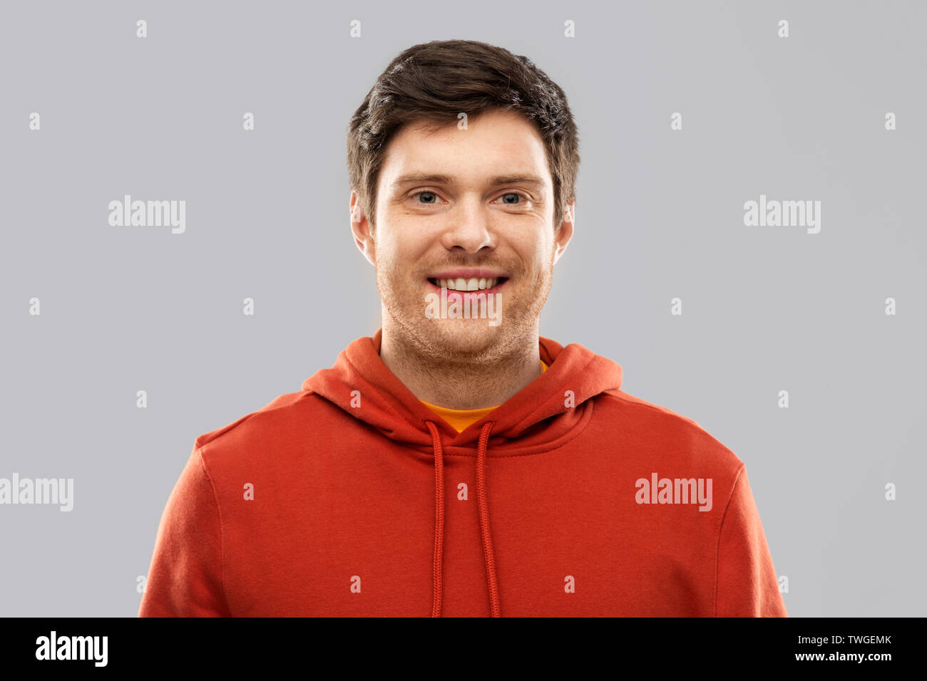 smiling young man in red hoodie over grey Stock Photo