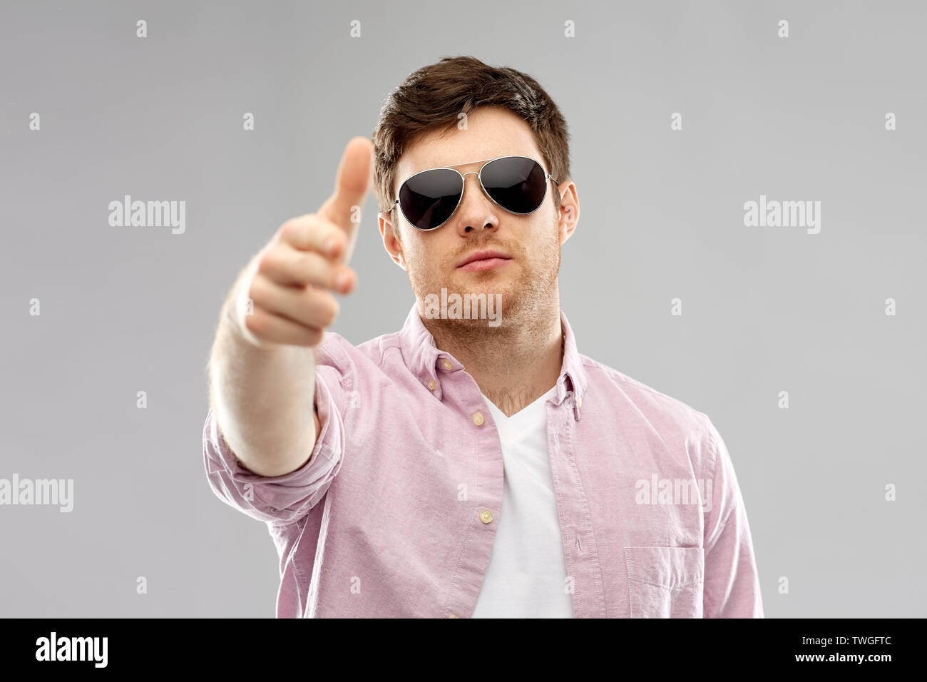 young man in sunglasses making hand gun gesture Stock Photo