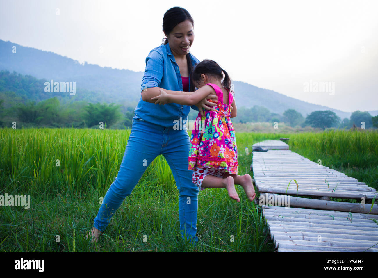 Help Cross Stream Mother help her child to cross stream, mother lifting daughter in rice ...