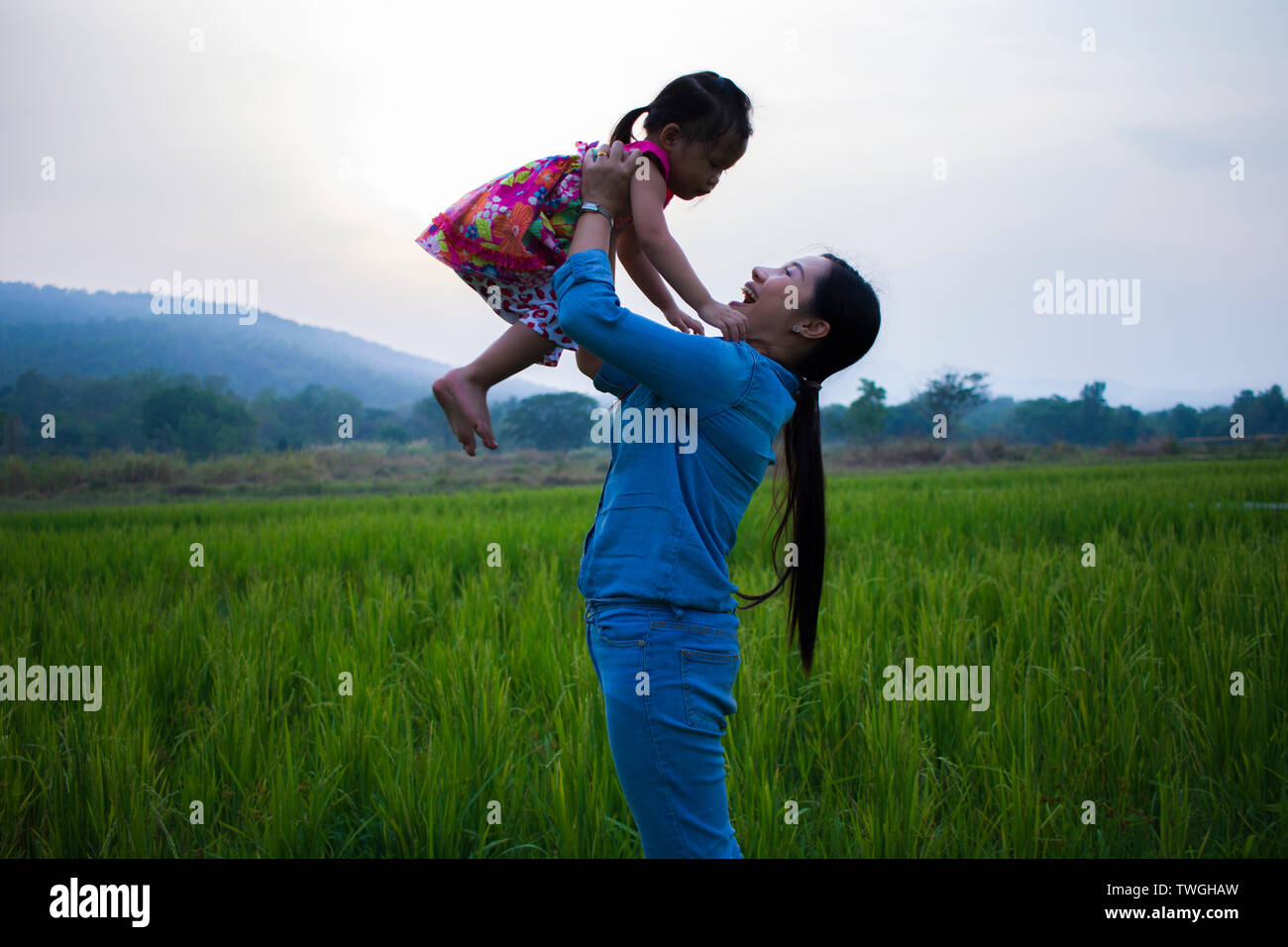 Happy Mother and her child play outdoors having fun, Green  rice field back ground. High resolution image gallery. Stock Photo