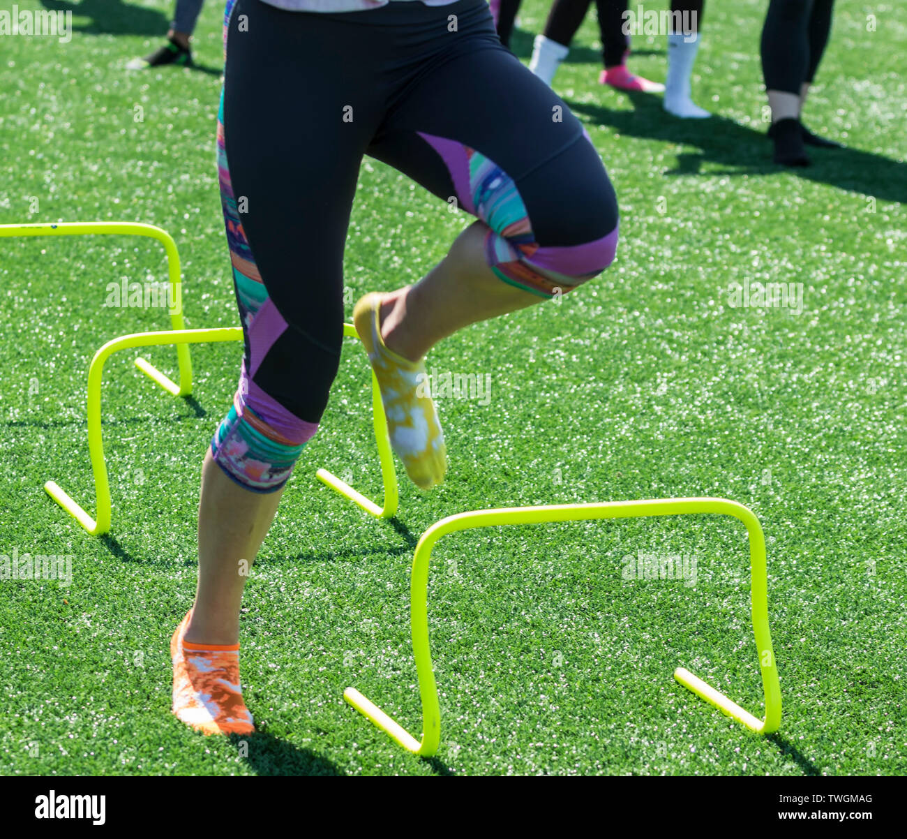 A track athlete is performing speed and agility drills over yellow mini