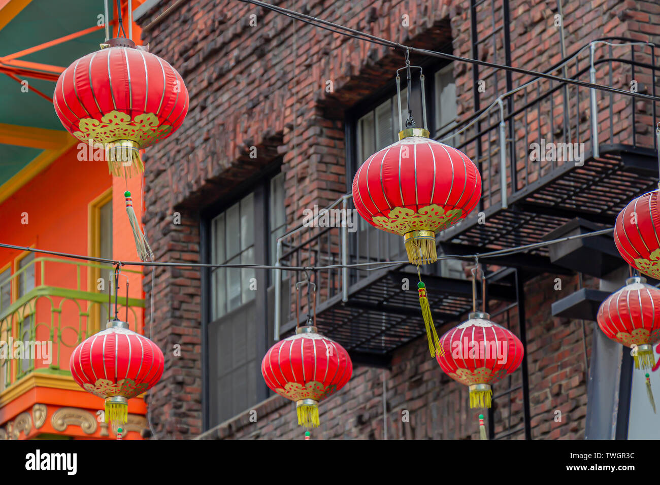 Red-and-gold Chinese lanterns in front of an old brick building in San Francisco, California, USA. Stock Photo