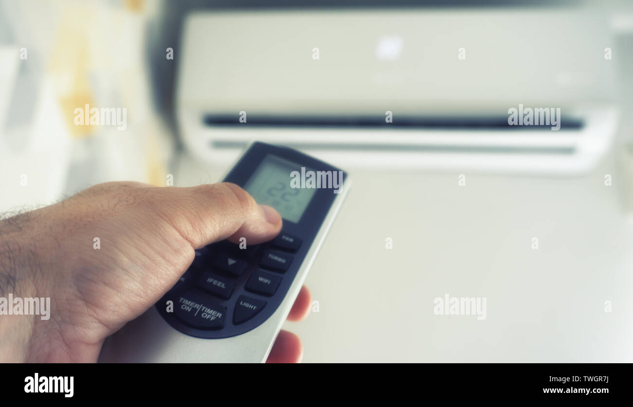 Hand hold remote control directed on the air conditioner Stock Photo