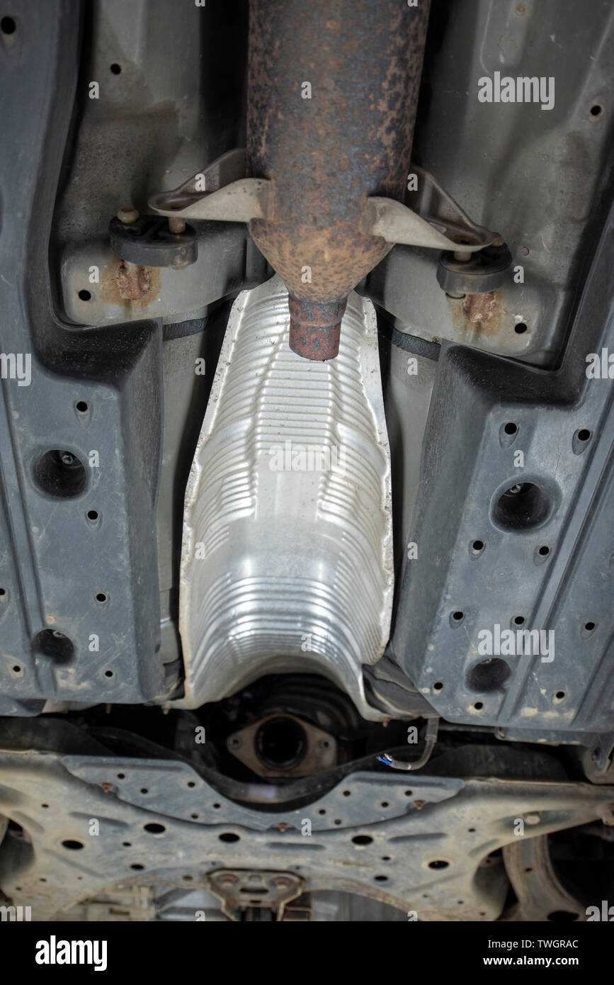 Toyota Prius, stolen Catalytic Converter. View underneath vehicle from a mechanics inspection pit, showing location of missing and damaged components. Stock Photo