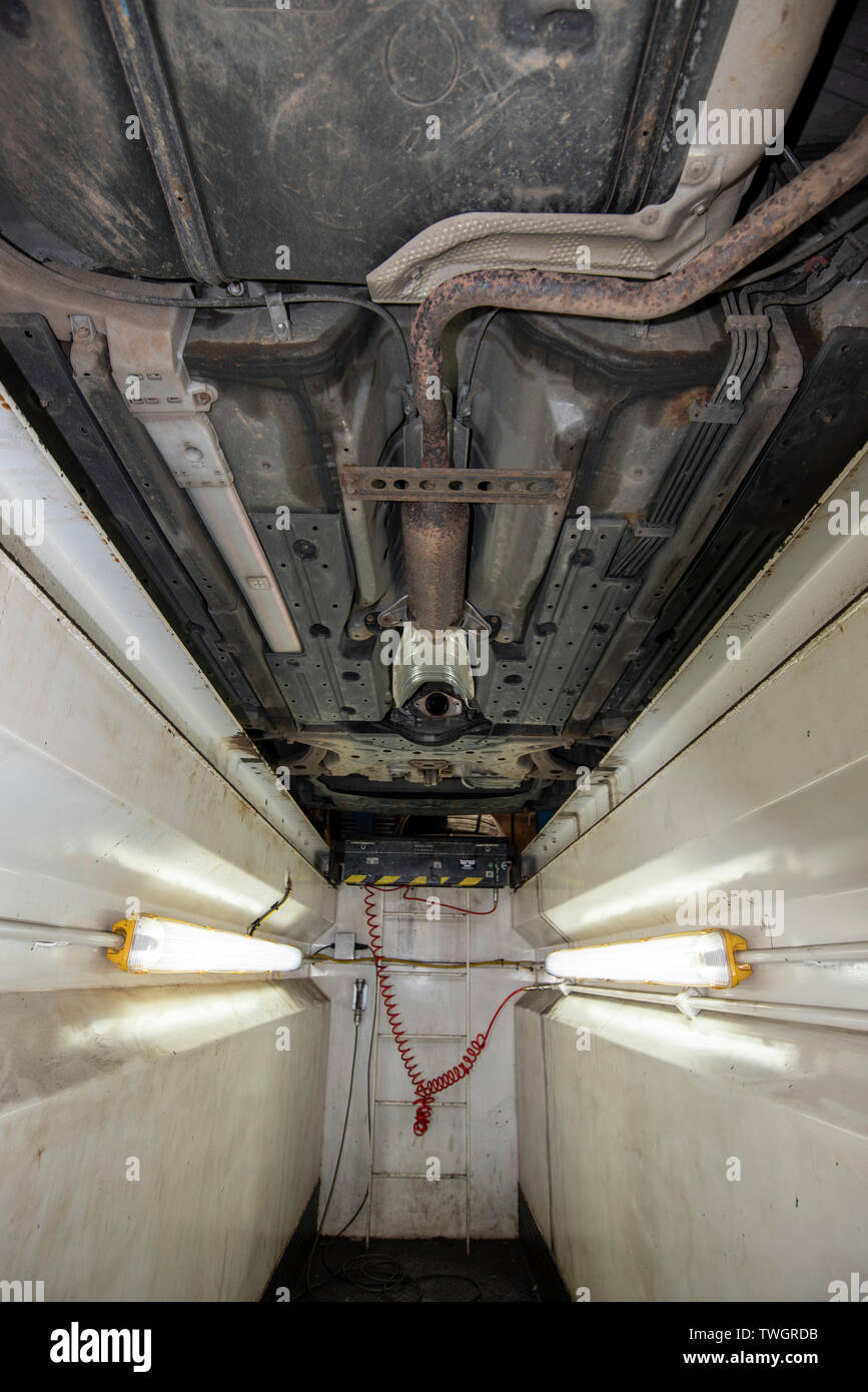 Toyota Prius Hybrid, stolen Catalytic Converter. Underneath vehicle from a mechanics inspection pit, showing location, missing and damaged components. Stock Photo