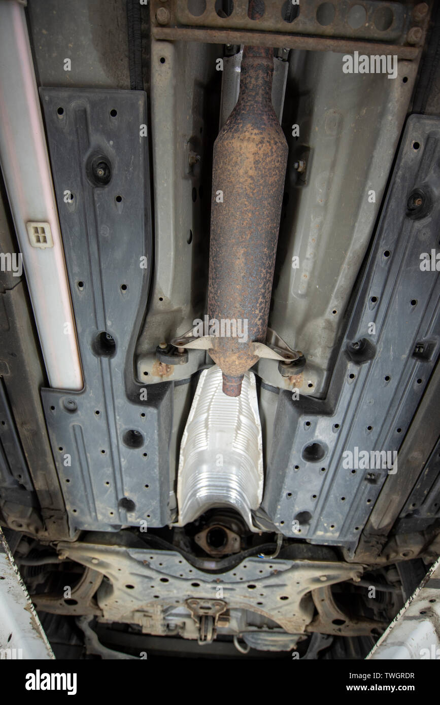 Toyota Prius Hybrid, stolen Catalytic Converter. Underneath vehicle from a mechanics inspection pit, showing location, missing and damaged components. Stock Photo