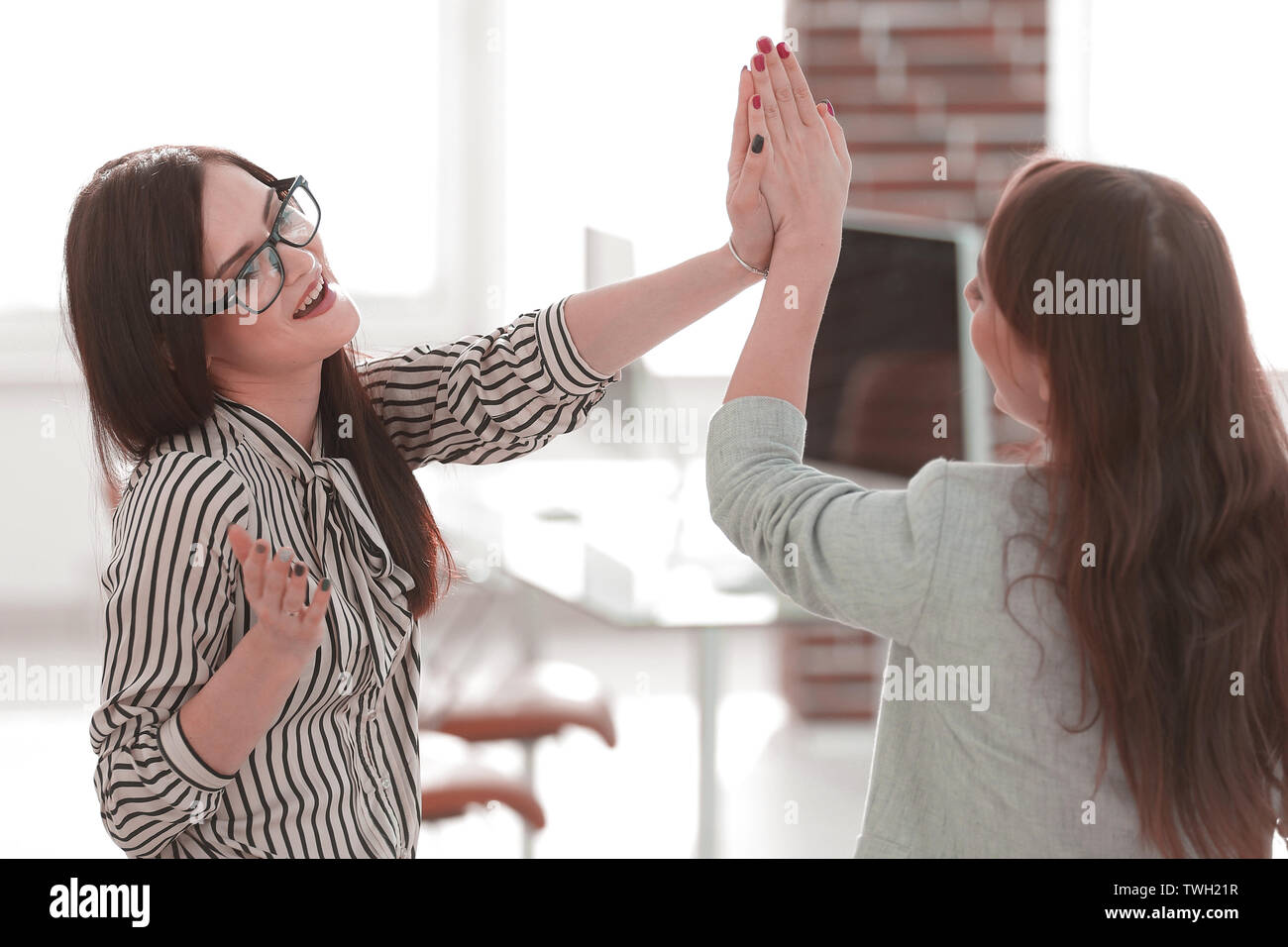 two young co-workers giving each other a high five Stock Photo - Alamy