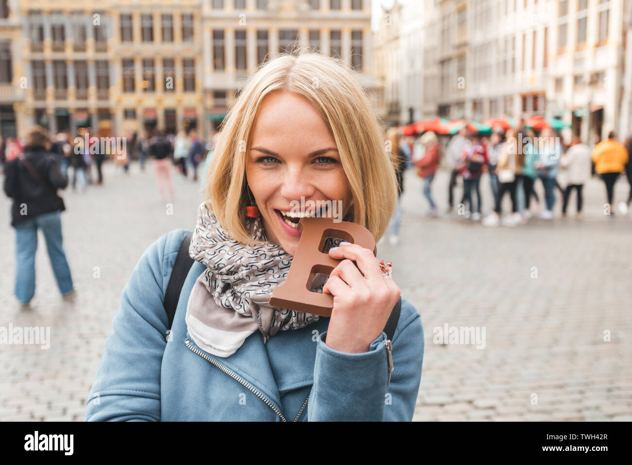 Woman tourist bites a bar of chocolate at the Grand Place in Brussels
